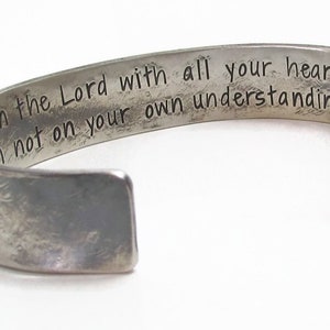 Puede incluir: Pulsera de plata con una inscripci&oacute;n grabada: "Conf&iacute;a en el Se&ntilde;or con todo tu coraz&oacute;n, y no te apoyes en tu propia inteligencia."