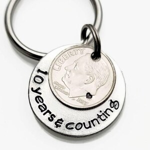 May include: Silver keychain with a dime and the words "10 Years & Counting" engraved on it.