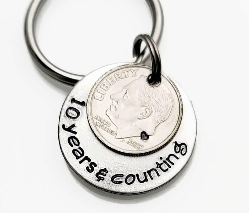 May include: Silver keychain with a dime and the words "10 Years & Counting" engraved on it.