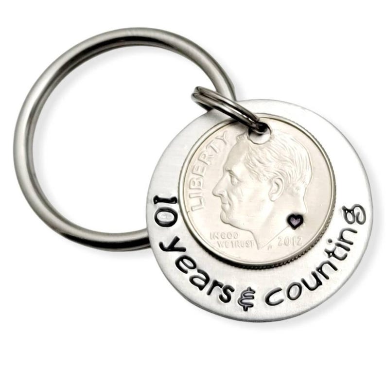 May include: Silver keychain with a dime and the inscription "10 years & counting" with a small heart.