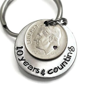 May include: Silver keychain with a dime coin and the text "10 years & counting".