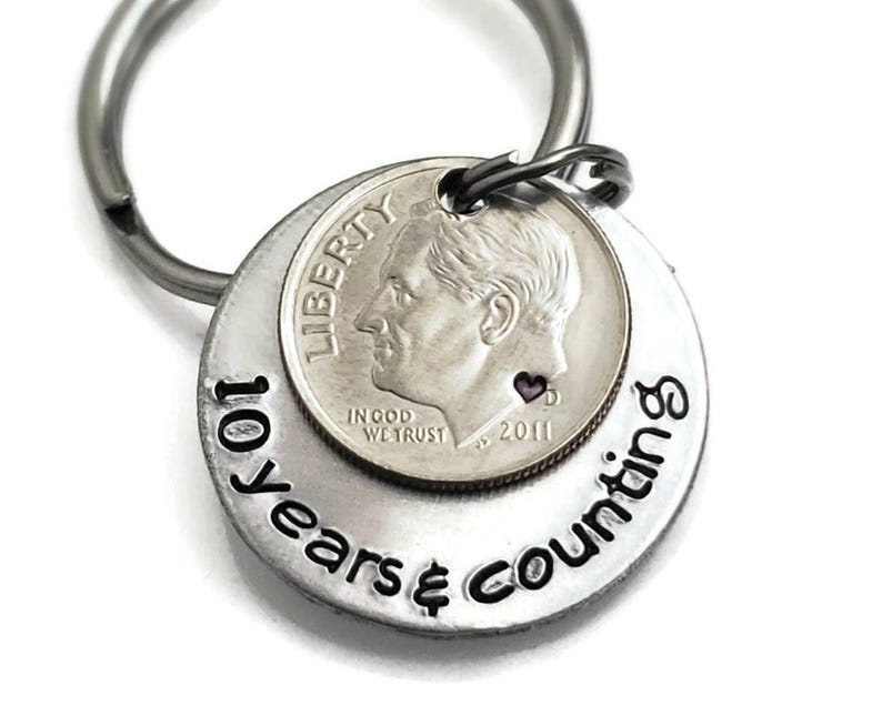 May include: Silver keychain with a dime coin and the text "10 years & counting".