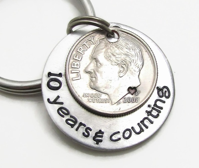 May include: Silver keychain with a dime and the inscription "10 years & counting".