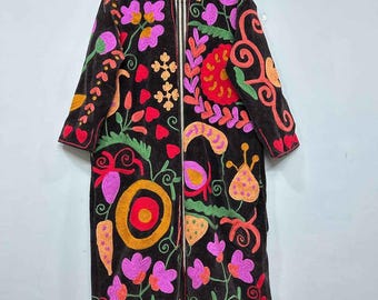 May include: A long, black coat with vibrant floral embroidery in shades of pink, orange, green, and red. The coat features a high collar and a full-length design, with intricate patterns adorning the front and sleeves. The embroidery includes flowers, hearts, and other decorative elements.
