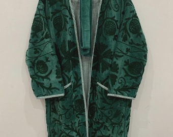 May include: A dark green robe with a floral pattern and white trim, hanging on a wooden hanger. The robe has a matching belt and a striped interior lining. The floral design includes pomegranate and leaf motifs.