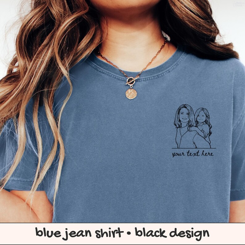 Puede incluir: Camiseta azul vaquera con un dibujo lineal negro de una madre y un ni&ntilde;o. La camiseta tiene el texto "your text here" debajo del dibujo. La camiseta es de color azul liso.