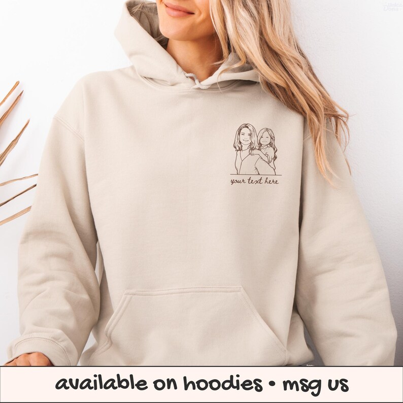 Puede incluir: Una sudadera con capucha beige con un bolsillo delantero y una capucha. La sudadera con capucha presenta un dibujo lineal negro de dos personas con el texto "your text here" debajo. La parte inferior de la imagen tiene el texto "available on hoodies &bull; msg us".