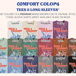 May include: A collection of Comfort Colors t-shirts in various colors including white, ivory, blossom, berry, bay, moss, light green, crimson, yam, espresso, chambray, blue jean, navy, grey, pepper, and black, each featuring the text FERAL & PREGNANT.