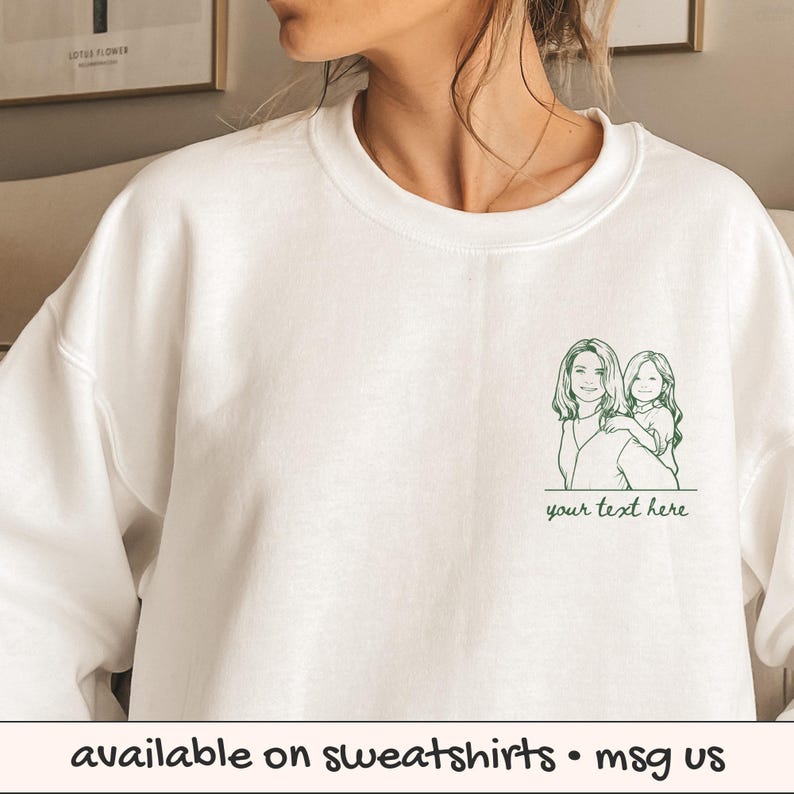 Puede incluir: Sudadera blanca con un dibujo lineal verde de una mujer y un ni&ntilde;o, con el texto "your text here" debajo. La parte inferior de la imagen tiene el texto "available on sweatshirts &bull; msg us".