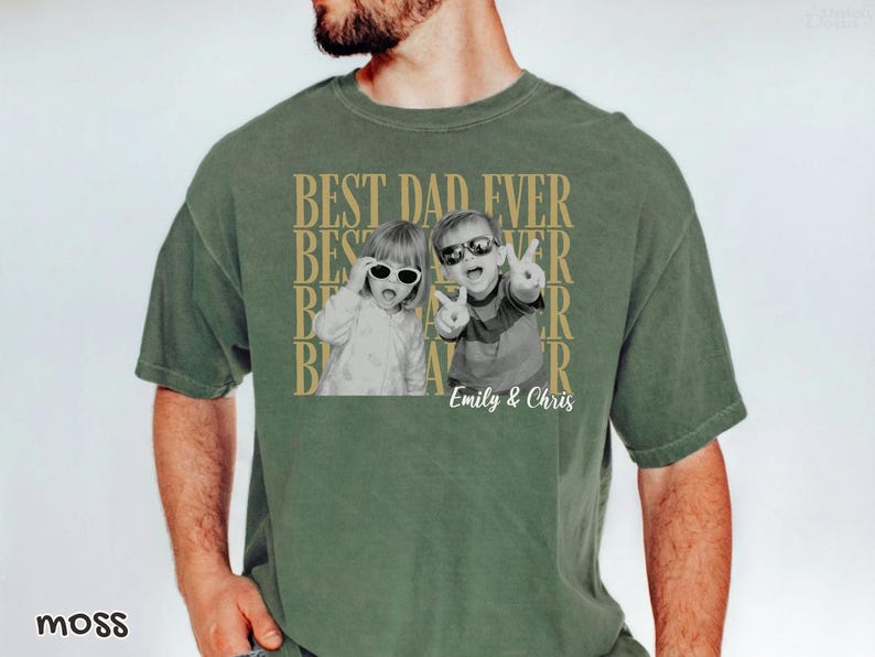 Pu&ograve; includere: T-shirt verde muschio con una foto in bianco e nero di due bambini con occhiali da sole. Le parole "BEST DAD EVER" sono stampate in oro, con i nomi "Emily & Chris" sotto. La maglietta ha una vestibilit&agrave; rilassata.
