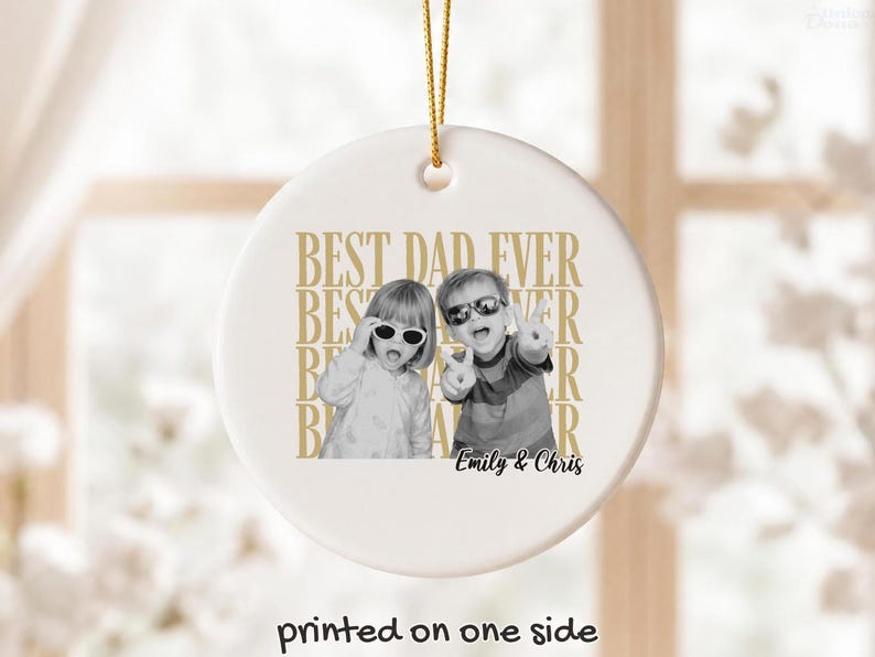 Pu&ograve; includere: Un ornamento natalizio rotondo in ceramica bianca con un cordino dorato per appenderlo. Presenta una foto in bianco e nero di due bambini con occhiali da sole. Il testo "BEST DAD EVER" &egrave; stampato in oro, con i nomi "Emily & Chris".