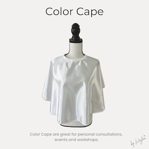 May include: A white satin color cape displayed on a black mannequin. The text Color Cape appears at the top, and the text Color Cape are great for personal consultations, events and workshops. appears at the bottom with the brand name by Weyfeen.