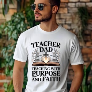 May include: White t-shirt with the text "TEACHER DAD" above an open book with a cross and the words "TEACHING WITH PURPOSE AND FAITH". The design includes leaves and a glowing light.