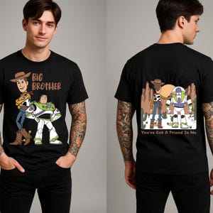 May include: Black t-shirt featuring cartoon characters Woody and Buzz Lightyear from Toy Story. The front of the shirt has the text "Big Brother". The back of the shirt has the text "You've Got A Friend In Me".