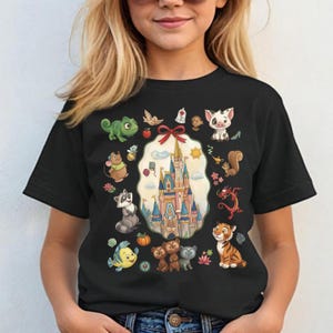 May include: Black t-shirt featuring a colorful graphic of a castle surrounded by various cartoon characters. The design includes a castle, animals, and other whimsical elements. The shirt is worn by a person.