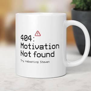 May include: White ceramic mug featuring the text "404: Motivation Not found" in black, with a red warning triangle. The mug also includes the text "Try rebooting Steven".