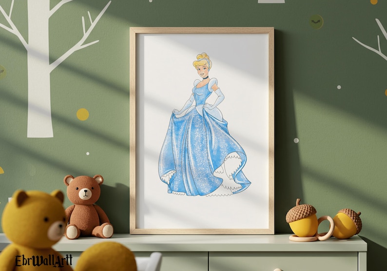 May include: A framed watercolor print of Cinderella in a light blue ball gown. The artwork features a blonde-haired woman with a choker and gloves. The print is displayed on a green wall with a tree and yellow accents. A brown teddy bear and yellow acorn mugs are in the foreground.