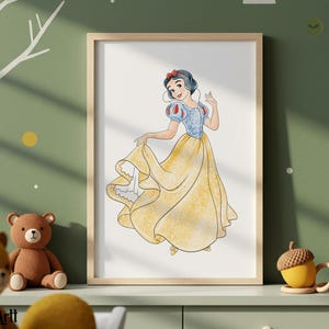 May include: A framed watercolor print of Snow White in a yellow gown with a blue bodice and red accents. The artwork is displayed on a light green wall with a teddy bear and acorn-shaped mugs in the foreground.