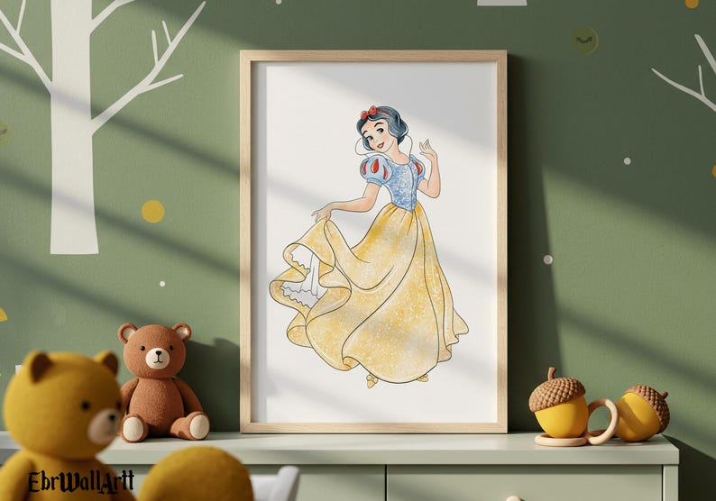 May include: A framed watercolor print of Snow White in a yellow gown with a blue bodice and red accents. The artwork is displayed on a light green wall with a teddy bear and acorn-shaped mugs in the foreground.