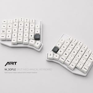 Puede incluir: Dos teclados mecánicos divididos blancos con teclas blancas y detalles negros. Los teclados tienen un diseño ergonómico curvo. El texto "ART W_SOFLE SPLIT MECHANICAL KEYBOARD" es visible.
