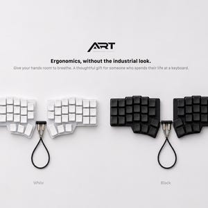 May include: Two split ergonomic keyboards, one white and one black, each featuring a unique key layout and a central connecting cable. The text ART, Ergonomics, without the industrial look. Give your hands room to breathe. A thoughtful gift for someone who spends their life at a keyboard. is visible above the keyboards.