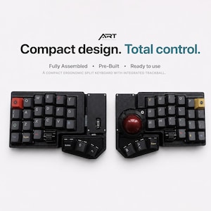 Könnte beinhalten: Eine schwarze ergonomische Split-Tastatur mit Trackball und roten und gelben Tasten. Die Tastatur ist in zwei Teile geteilt und trägt den Text "Compact design. Total control."