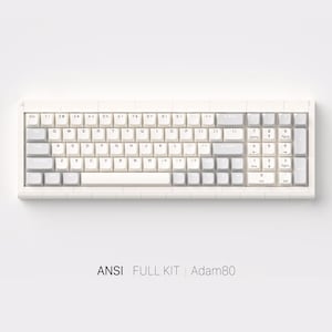 Puede incluir: Un teclado mecánico blanco y gris con un juego completo de teclas. El teclado tiene forma rectangular con un marco blanco y teclas grises y blancas. El texto "ANSI FULL KIT Adam80" está impreso en la parte inferior.
