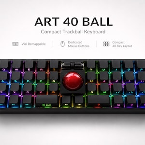 Peut inclure: Un clavier compact noir à 40 touches avec une boule de commande rouge centrale et des boutons de souris intégrés. Les touches disposent d'un rétroéclairage RVB. Le texte indique ART 40 BALL Compact Trackball Keyboard, Vial Remappable, Dedicated Mouse Buttons, Compact 40-Key Layout.