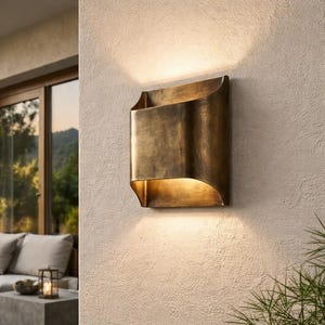 May include: A bronze-colored outdoor wall sconce with a curved design. The light fixture is mounted on a textured, light-colored wall. The sconce emits a warm glow, creating a welcoming ambiance. The fixture is approximately 12 inches tall and 8 inches wide.