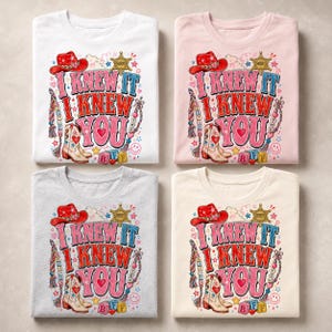 May include: Four t-shirts in white, light pink, heather gray, and cream, each featuring a graphic print with a red cowboy hat, a cowboy boot, a sheriff star, and the text I KNEW IT I KNEW YOU, alongside colorful hearts, stars, and beads.