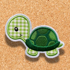 Może przedstawiać: Aplikacja żółwia w zielono-białe kratki z zielonym pancerzem i białymi szwami.