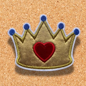 Op de afbeelding: Een gouden kroon met een rood hart in het midden. De kroon heeft vijf punten en blauwe accenten.