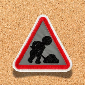 May include: A red and white triangular road sign with a black silhouette of a worker digging a hole. The sign warns of road works.