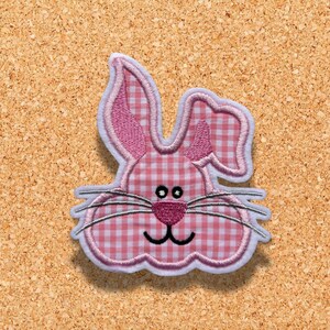 May include: Pink and white gingham bunny face applique with embroidered details. The bunny has a pink nose, white whiskers, and black eyes.