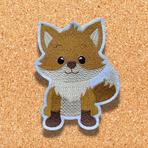 Puede incluir: Un zorro bordado en marrón y blanco con un contorno azul claro. El zorro está de pie sobre sus patas traseras con la cola enroscada detrás de él.
