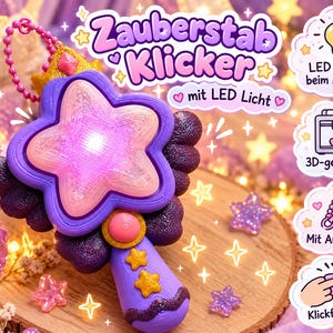 Könnte beinhalten: Ein violetter, sternförmiger Zauberstab mit einem rosa Zentrum, das durch ein LED-Licht leuchtet. Der Stab hat eine goldene Krone, dunkelviolette flügelartige Akzente und einen Griff mit gelben Sternen. Inklusive einer rosa Kugelkette.
