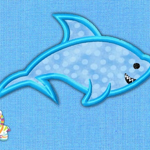 May include: A light blue embroidered shark with white polka dots and a smiling mouth. A small, colorful zebra is to the left of the shark. The background is a light blue fabric.