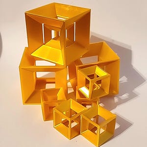 May include: A collection of nested yellow cube structures, each featuring an open-frame design with smaller cubes contained within larger ones, creating a geometric arrangement of multiple hollow square forms in varying sizes.