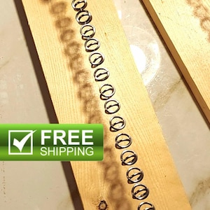 May include: A long, rectangular piece of light-colored wood with a vertical white golf tee at each end. A series of silver-toned metal rings are threaded onto a thin wire that connects the two golf tees, creating a straight line of hardware.