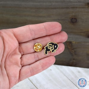May include: A gold-colored pin with a black and gold buffalo logo, and a separate gold pin back. The buffalo pin is a collegiate licensed product. The pin is small and likely made of metal.