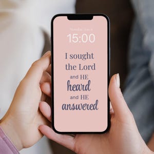 May include: A smartphone displays a pink screen with the text "I sought the Lord and HE heard and HE answered." The time is 15:00, and the date is Monday, Jan 6. The phone is held in two hands.
