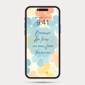 Può includere: Uno smartphone con uno sfondo floreale con fiori blu, pesca e gialli. Lo schermo mostra la data, l'ora e il testo "Because He lives, we can face tomorrow."