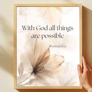 May include: Framed art print featuring the text "With God all things are possible" from Matthew 19:26. The artwork displays a floral design in shades of beige and brown, set against a white background. The frame is a light wood color.