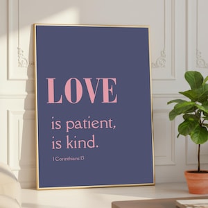 May include: A framed print with the words "LOVE is patient, is kind." in pink lettering on a dark blue background. The frame is gold. The text "I Corinthians 13" is at the bottom.