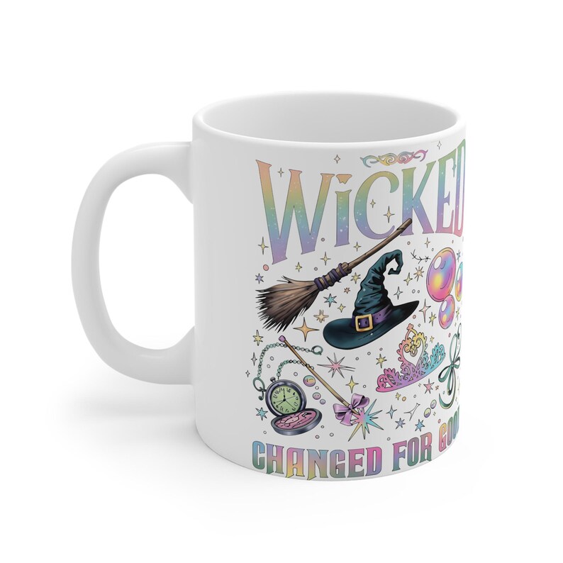 May include: White ceramic mug with the word "WICKED" in rainbow lettering, along with illustrations of a witch's hat, broom, and other magical elements. The phrase "CHANGED FOR GOOD" is also printed on the mug.