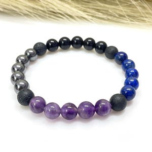 Può includere: Un braccialetto di perline con una varietà di perline di pietre naturali. Il braccialetto include perline di ametista lucida, onice nero, ematite e lapislazzuli. Le perline sono infilate su un cordoncino elastico, creando un braccialetto elasticizzato.