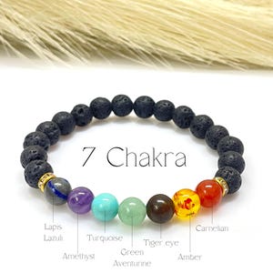 May include: A beaded bracelet featuring seven chakra stones in various colors, including amethyst, turquoise, and amber, interspersed with black lava beads. The text "7 Chakra" is displayed on the image, along with the names of the stones.