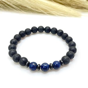May include: Black lava rock bead bracelet with dark blue lapis lazuli beads and dark gray spacers. The bracelet is strung on an elastic band. The beads are approximately 0.3 inches in diameter.