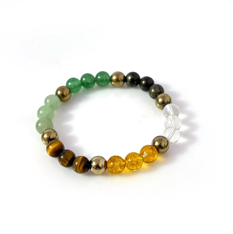 May include: A multi-coloured beaded bracelet with green, gold, yellow, and clear gemstones. The bracelet includes green jade, tiger's eye, and pyrite beads. The beads are strung together on an elastic band.