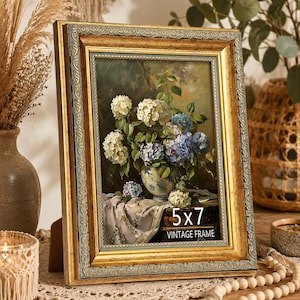 May include: A rectangular 5x7 vintage frame with an ornate gold and grey border. The frame contains a still life print of white and blue hydrangea flowers in a patterned vase resting on a draped cloth. The frame has a textured, metallic finish.